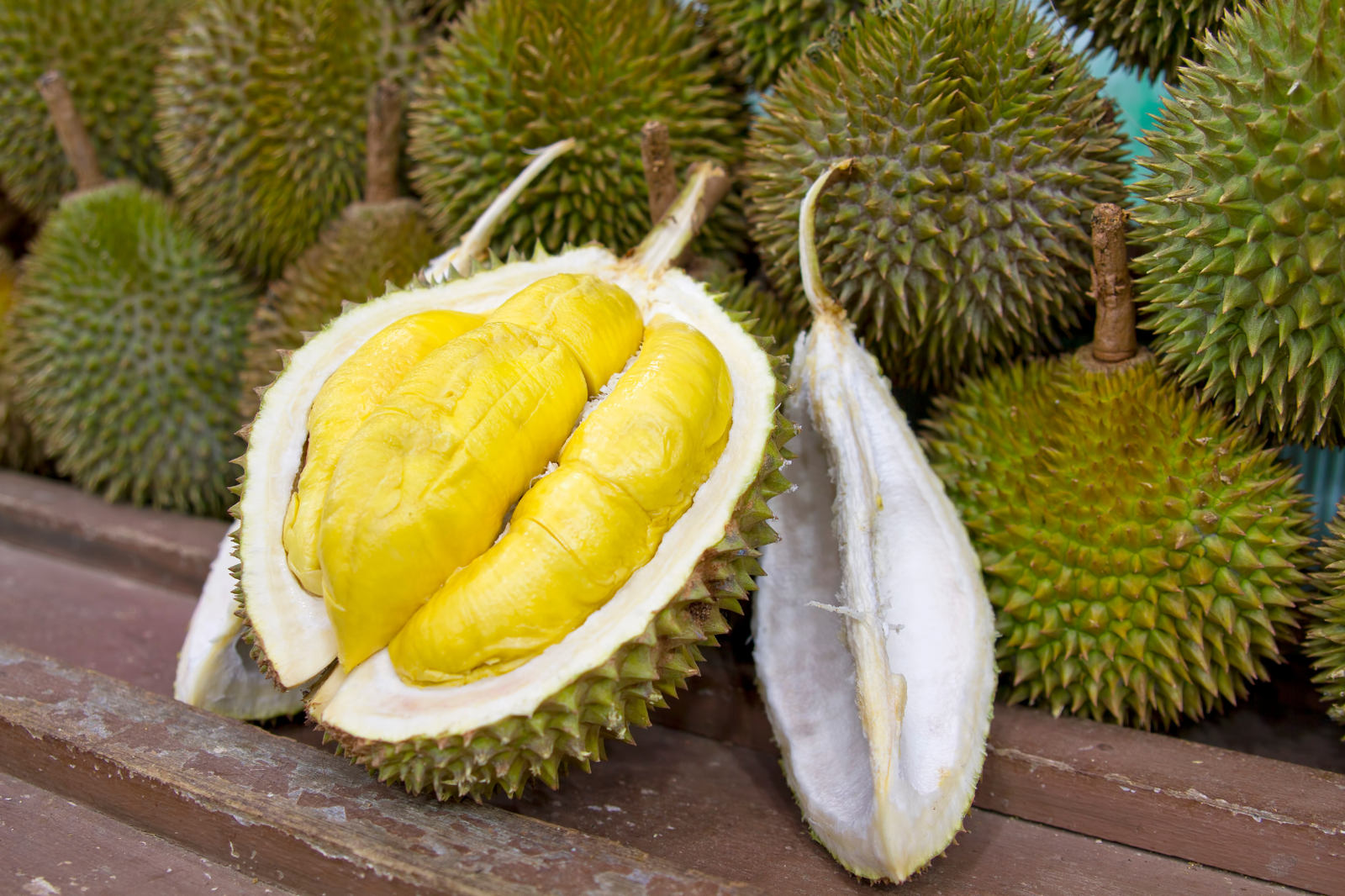 Durians with one fruit opened to show the yellow flesh